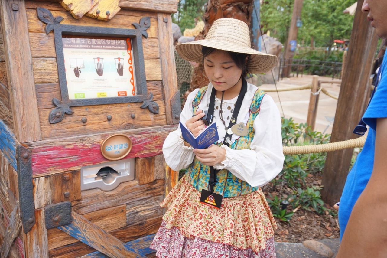 A Cast Member focuses on in interactive passport for guests exploring the park. Photo by J. Jeff Kober.